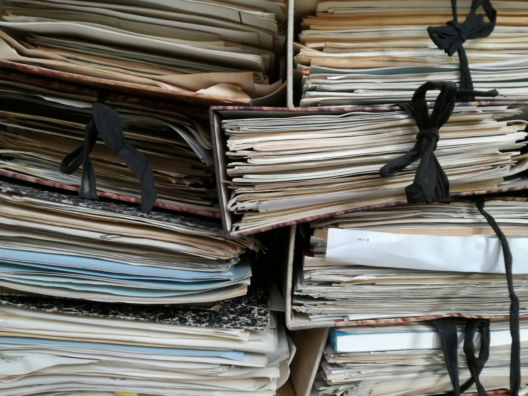 Pilhas de pastas de processos em papel amarradas com cordão